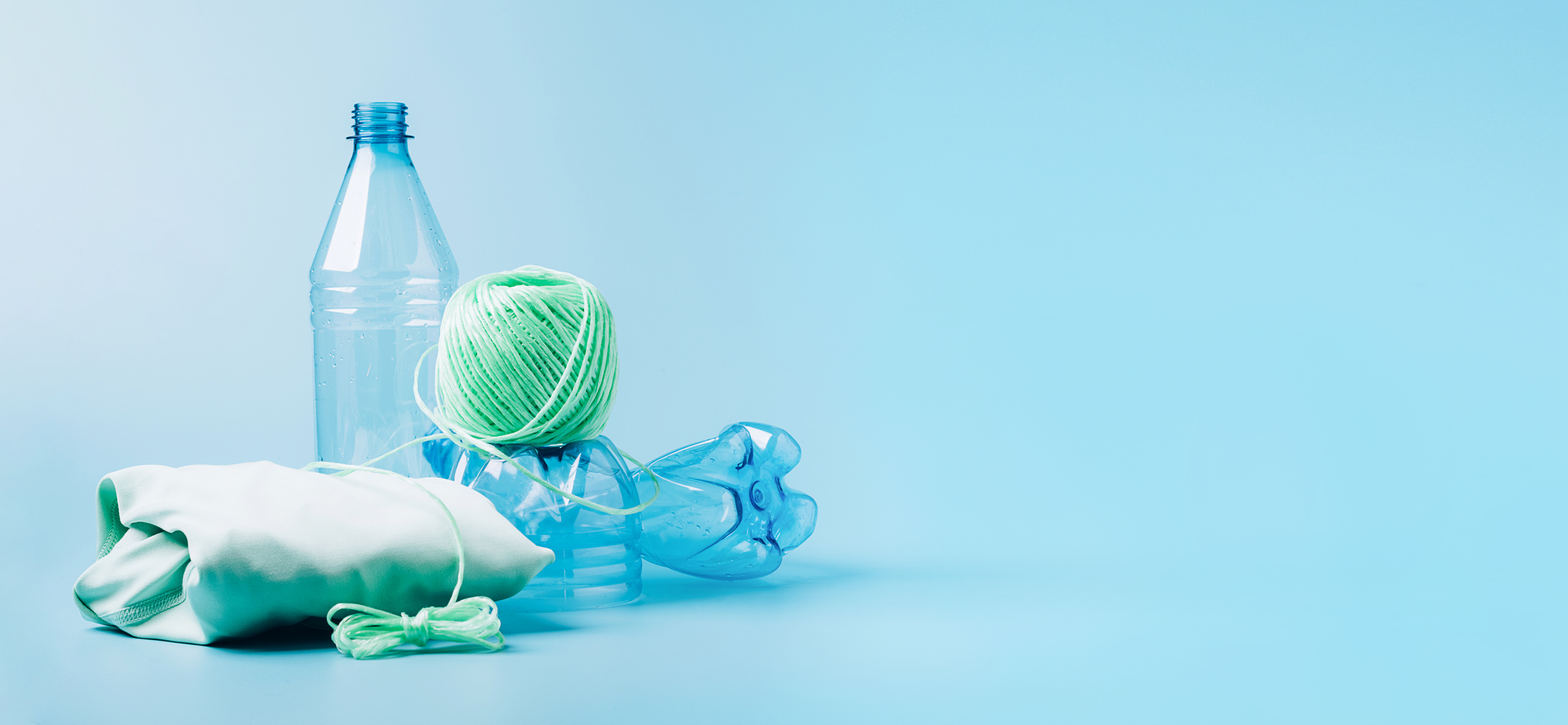 The Concept Recycling Plastic. Empty Plastic Bottle and Recycled Polyester Fiber, Synthetic Fabric Blue Background